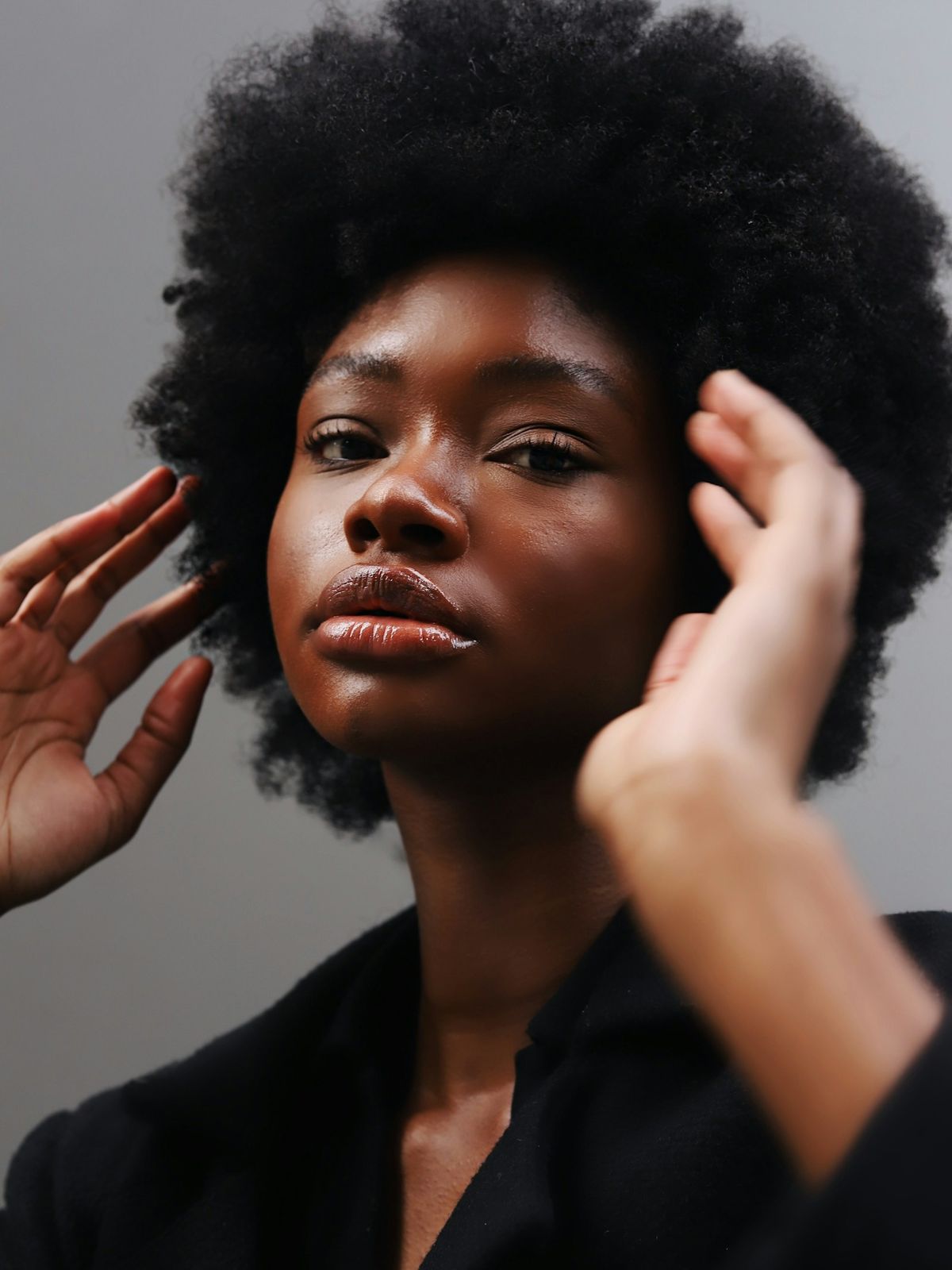 Hands shaping a client's natural afro